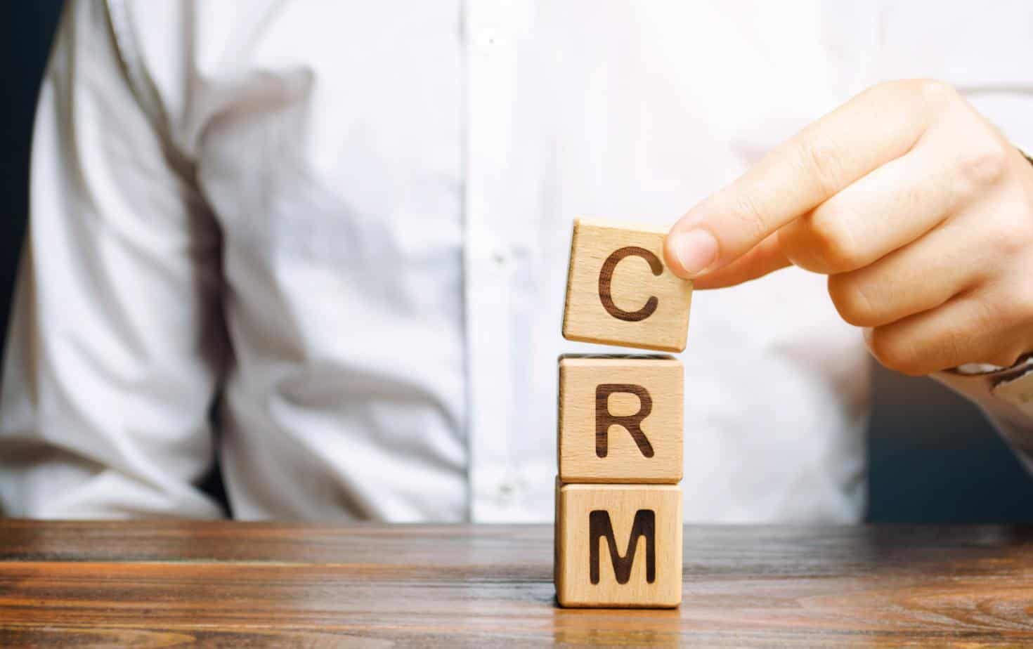 Wooden blocks with the word CRM (Customer Relationship Management) and businessman